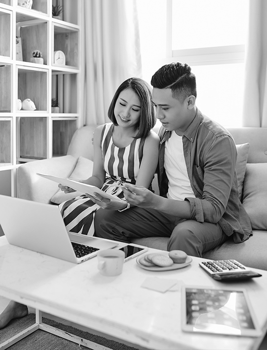 Asian couple at home sitting on couch reviewing documents
