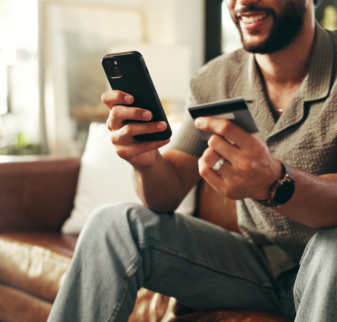 man holding debit card and mobile phone